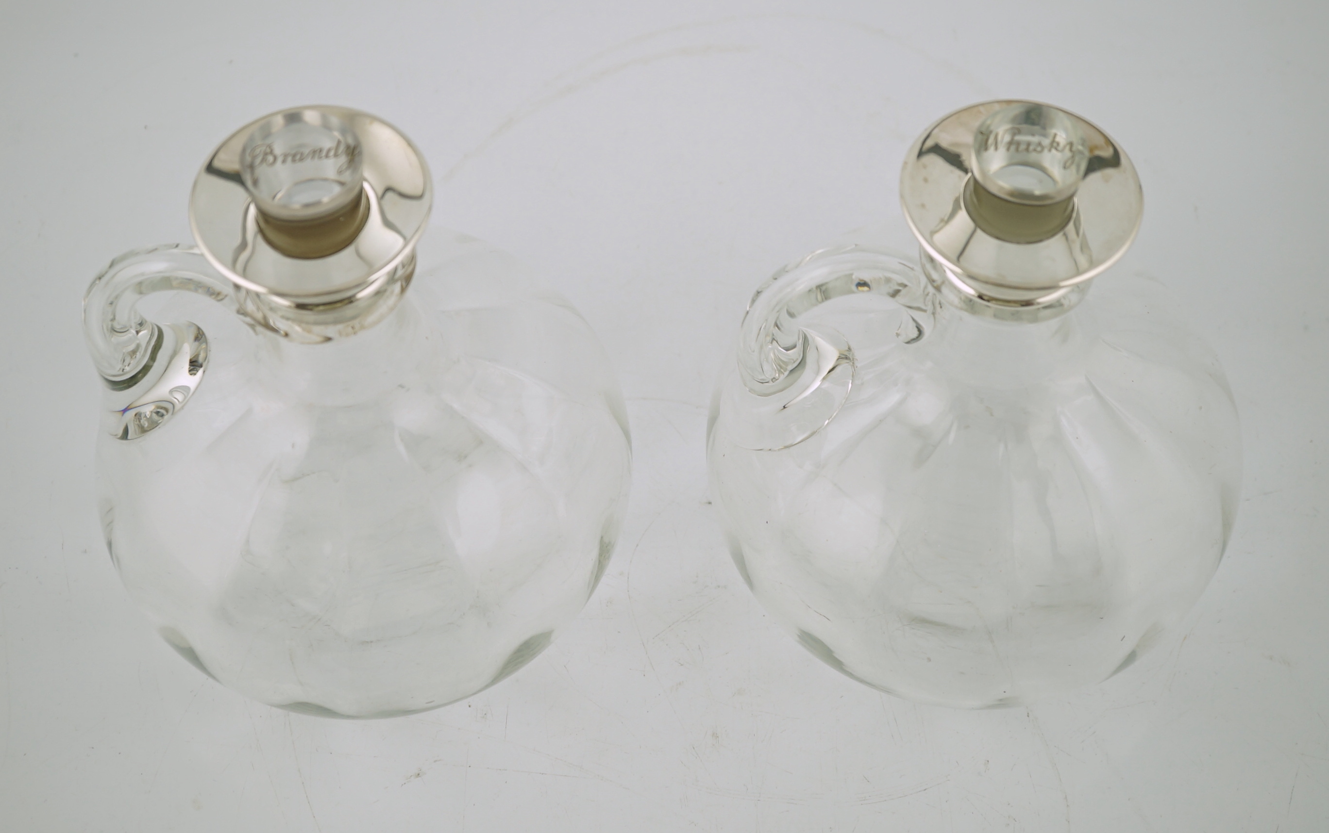 A pair of Edwardian silver mounted glass decanters, with stoppers etched 'Whisky' & 'Brandy', by Charles & George Asprey